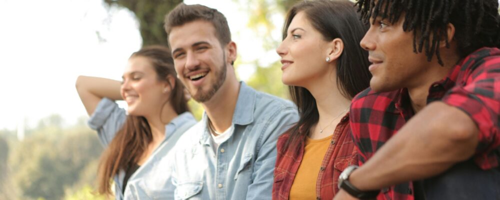 A group of four young adults laughing in the park